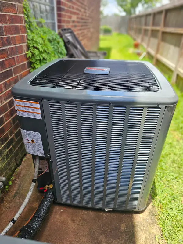 New outdoor AC condenser installed beside a brick home in Fort Bend County