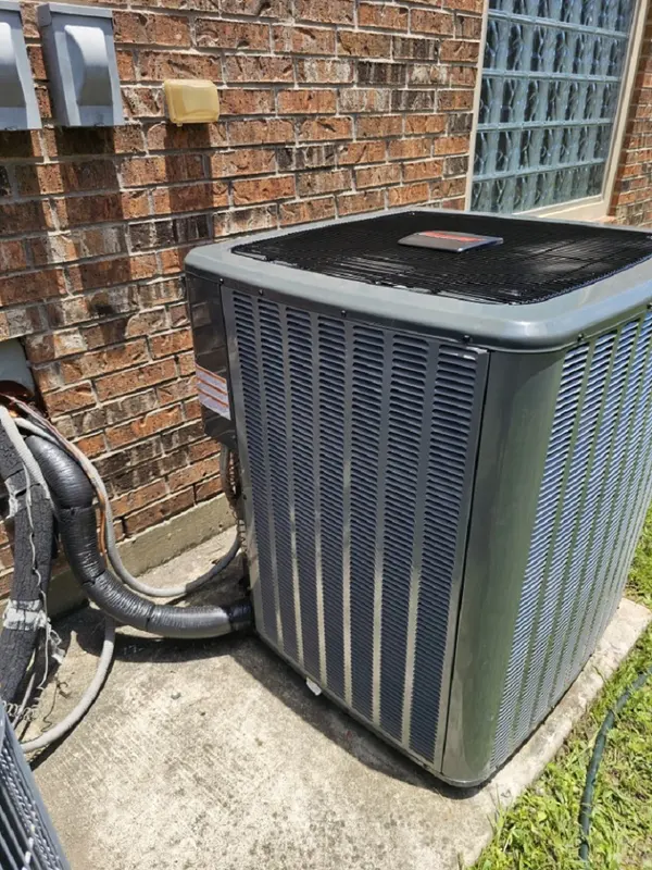 Outdoor AC unit on a fresh pad next to a brick home