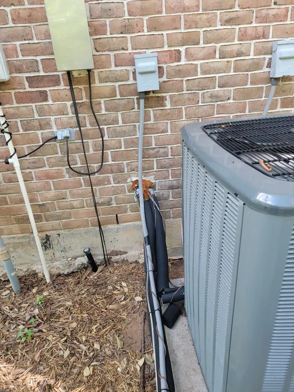 Outdoor AC unit and new line set on the side of a brick home