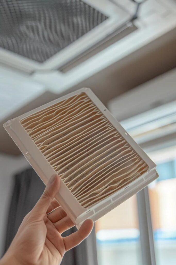 Close-up of a clean HVAC air filter held by a homeowner with the heat pump in the background